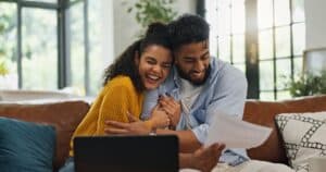 Couple reviewing financial documents while working on their laptop